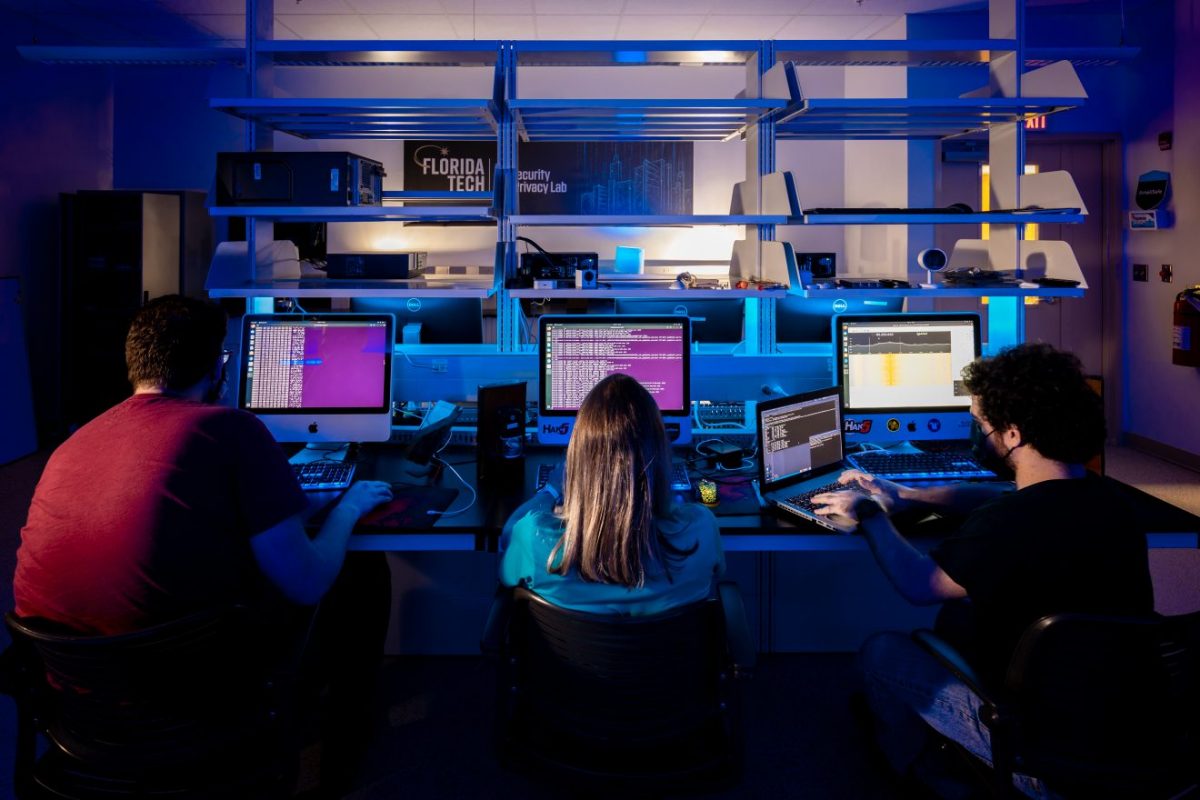 Three students sit at computers with their backs to the viewer as they work in Florida Tech's IoT Security and Privacy Lab.