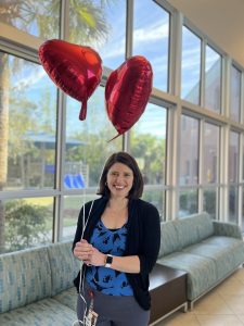 Kimberly Sloman holding two heart balloons after being informed of her award nomination and selection. 